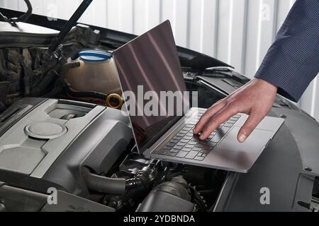 Car mechanic using computer in auto repair shop Stock Photo