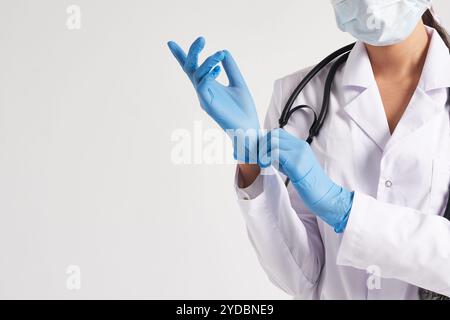 Young doctor putting on surgical gloves over white background Stock Photo