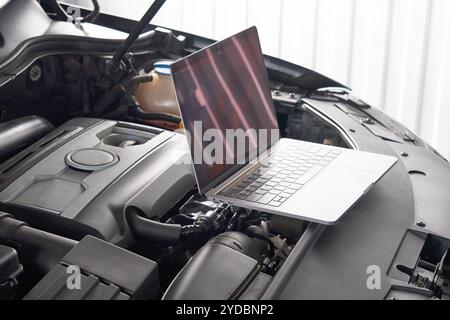 Laptop on a car in auto repair shop, Automobile mechanic repairman concept Stock Photo