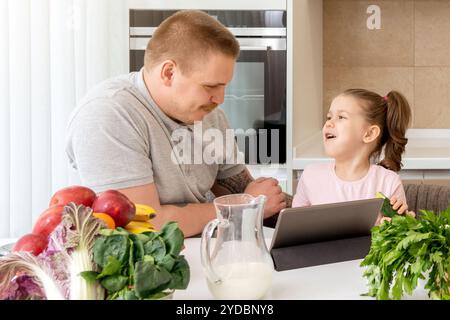 Father And Daughter Using Digital Tablet In Kitchen At Home Stock Photo