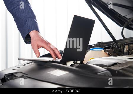 Car mechanic using computer in auto repair shop Stock Photo