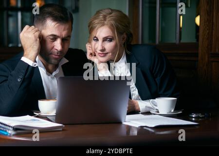Happy business people working together on laptop in a restaurant Stock Photo