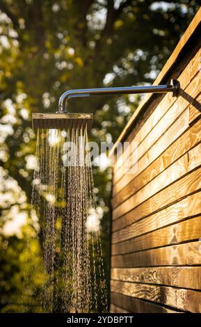 Outdoor shower with flowing water at sunset for showering before and after swimming in a pool Stock Photo