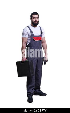 Worker wearing overalls standing and holding electric screwdriver or drill isolated on white background Stock Photo