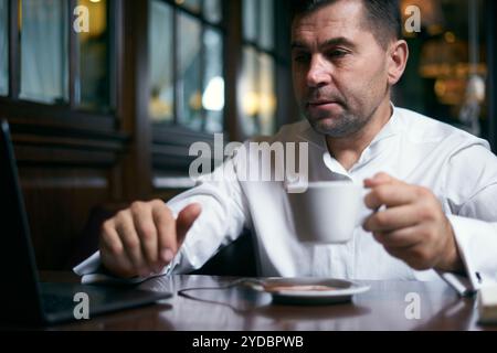 Businessman having coffee in a cafe while working on laptop Stock Photo