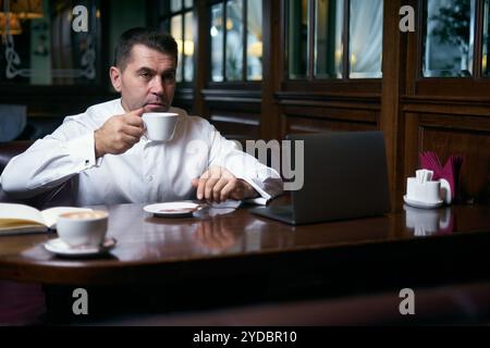 Businessman having coffee in a cafe while working on laptop Stock Photo