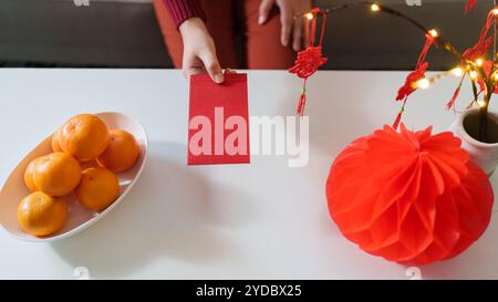 Asian Woman giving red envelope for Lunar New Year celebrations. Hand hold red packet thankful present Lunar New Year. Chinese t Stock Photo