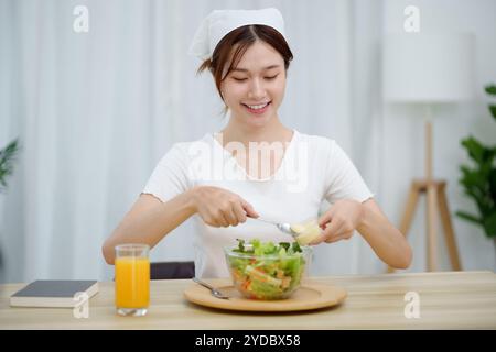 Portrait of happy playful asian girl eating fresh saladÂ in diet concept Stock Photo