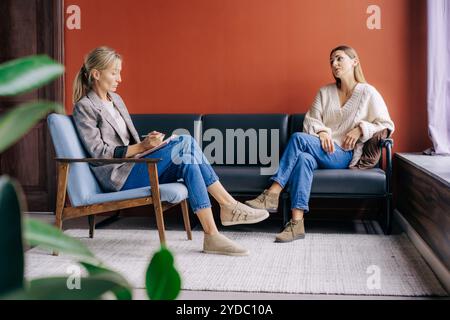 A female psychotherapist during a visit attentively listens and counseling a young woman talking about problems. Stock Photo