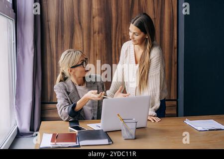 Two female colleagues at a working office place are discussing a project. Stock Photo