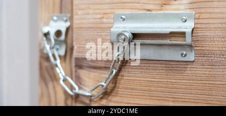 Close up of security door chain on wooden door Stock Photo