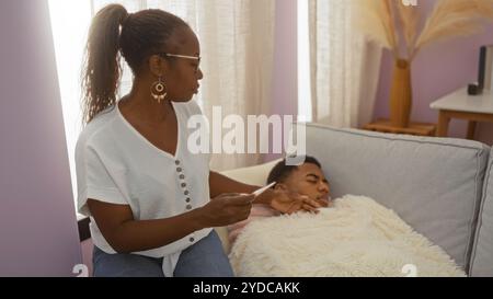 Mother holding thermometer checking on sick son in living room home environment depicting family love and care Stock Photo