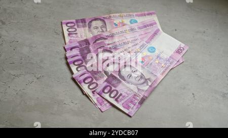 Philippine banknotes on a concrete surface showcasing the 100-peso bill. Stock Photo