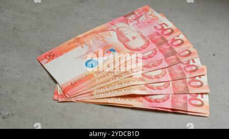 Philippine pesos banknotes are spread out on a concrete surface, highlighting the vibrant design and currency details. Stock Photo