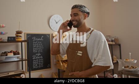 Handsome man with beard talking on phone while working in bakery shop Stock Photo