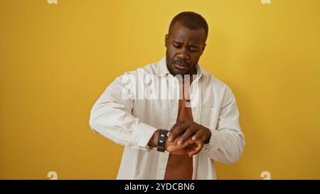 Handsome young man over isolated yellow background checking time on smartwatch Stock Photo
