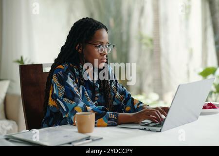 Focused Woman Typing on Laptop while Working at Home Stock Photo