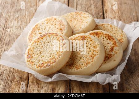 Porous Homemade English Crumpets close-up on parchment paper on old table. Horizontal Stock Photo