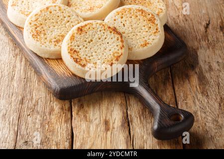 Close up of fresh golden crumpets on the wooden board on the table. Horizontal Stock Photo