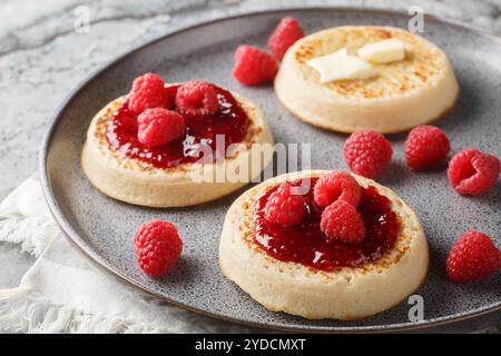 English style crumpets served with berries jam and butter closeup on the plate on the table. Horizontal Stock Photo