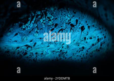 Bright blue dots on black background, oil stains movement, bright chemistry, surreal background, blue sky colour Stock Photo