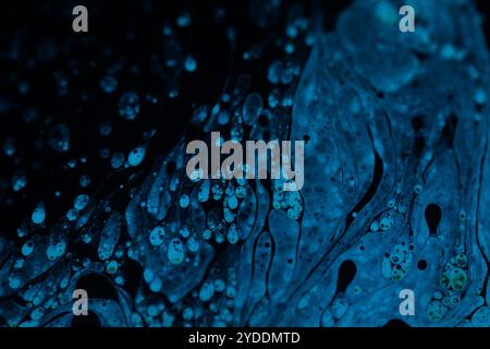 Bright blue dots on black background, oil stains movement, bright chemistry, surreal background, blue sky colour Stock Photo