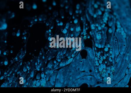 Bright blue dots on black background, oil stains movement, bright chemistry, surreal background, blue sky colour Stock Photo
