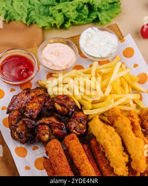 Fried nuggets and spicy chicken legs, wings and french fries potatoes Stock Photo