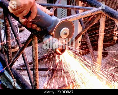 angle side disc grinder cutting steel with sparks, a handheld power tool used for grinding (abrasive cutting) and polishing, Angle grinders used in me Stock Photo