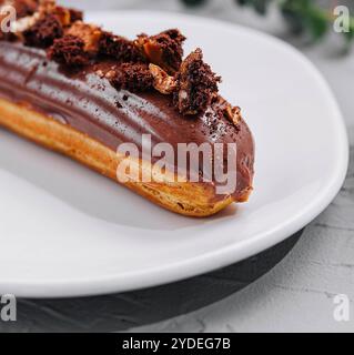 Eclair with Chocolate Cream and Hazelnuts closeup Stock Photo