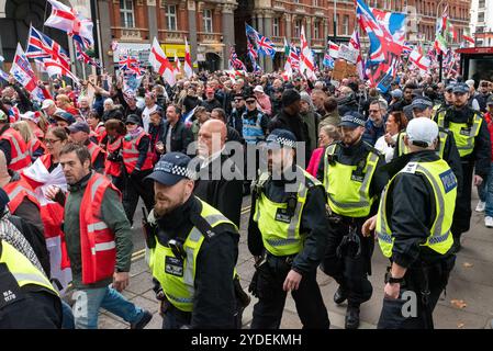 Westminster, London, UK. 26th Oct, 2024. Supporters of Stephen Yaxley-Lennon (AKA Tommy Robinson) are taking part in a protest march to Whitehall. Themes of the protest include immigration, and an opposing protest organised by Stand Up to Racism is marching to the other end of Whitehall. Metropolitan Police and units drafted in from elsewhere are attending in numbers to deter violence. Police escort for the protest march Stock Photo