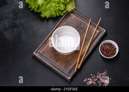 An empty white bowl and sticks on a wooden cutting board Stock Photo