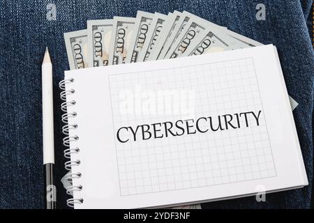 The concept of technology and development. Phrase, words, text CYBERSECURITY on a blank sheet of notepad against the background of dollar bills. Stock Photo