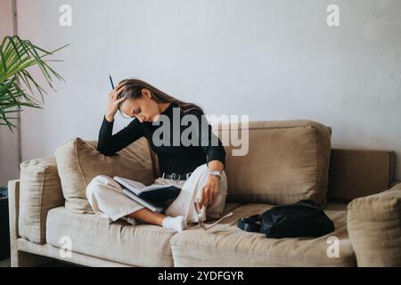 Young female student studying on a comfortable couch at home Stock Photo