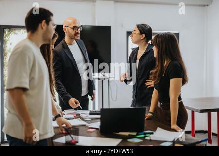 Students collaborating with professor on academic project in classroom setting Stock Photo