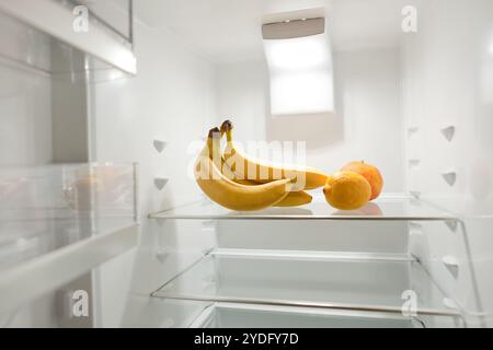 bunch of ripe bananas in empty refrigerator. View through the open refrigerator door. bananas at empty refrigerator Stock Photo