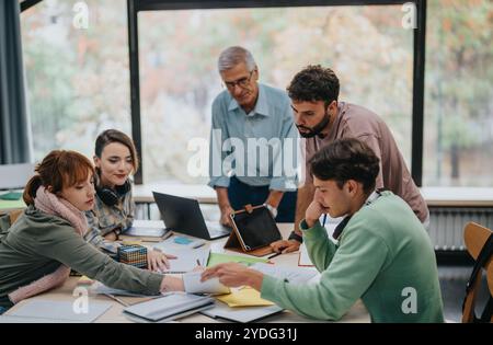 University students collaborating on project with guidance from senior professor Stock Photo
