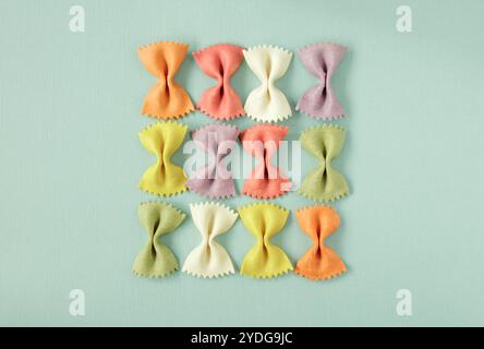 Large coloured Farfalle pasta arranged in a square on light green background Stock Photo