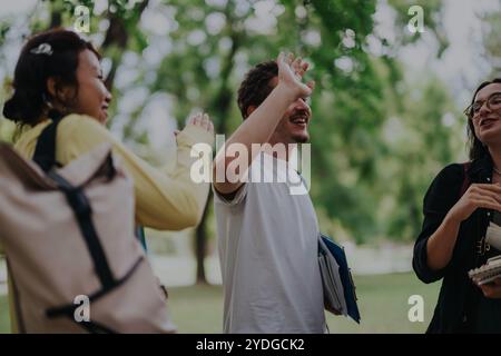 Multicultural students collaborating on assignments in a serene park setting Stock Photo