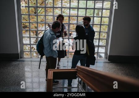 Students engaging in discussion with professor in university hallway Stock Photo