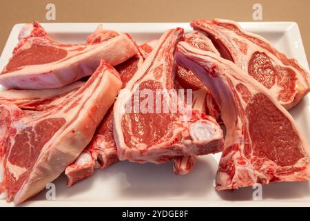 High quality New Zealand lamb ribs arranged on a white plate The marbled pink meat and fat layers highlight the freshness and excellent tenderness of Stock Photo