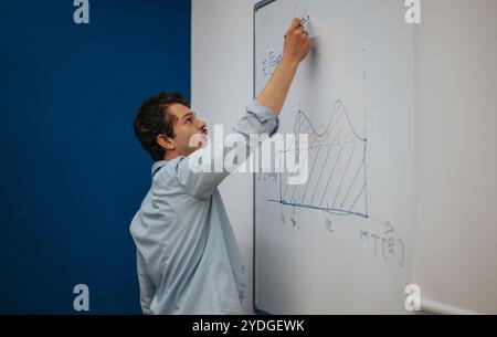 Young student writing mathematical equations on whiteboard in classroom Stock Photo