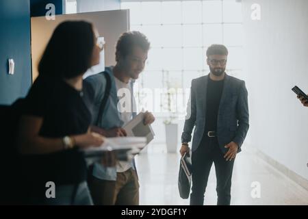 University students engaging with professor in hallway discussion Stock Photo