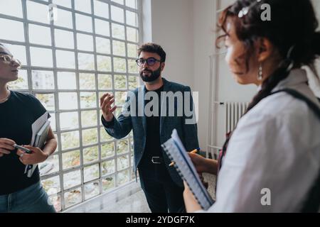 University professor engaging with students in a bright, open hallway Stock Photo
