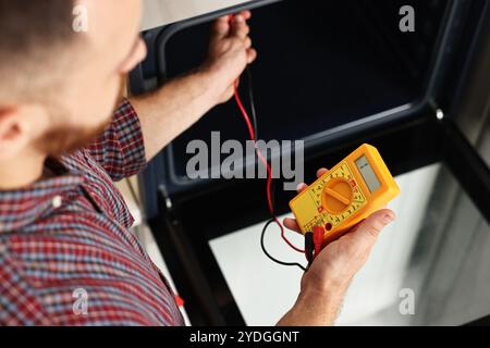 Repairman testing oven element with multimeter, closeup Stock Photo