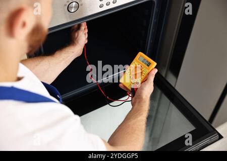 Repairman testing oven element with multimeter, closeup Stock Photo
