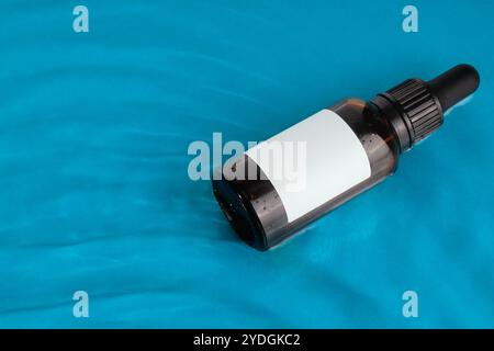 Amber Dropper Bottle with Blank Label on Blue Background Stock Photo