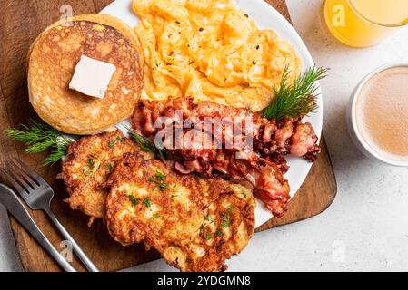 Full American Breakfast with scrambled eggs, bacon, hash browns and pancakes served with cooffee and orange juice, top view. Stock Photo