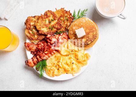 Full American Breakfast with scrambled eggs, bacon, hash browns and pancakes served with coffee and juice on white background, top view. Stock Photo