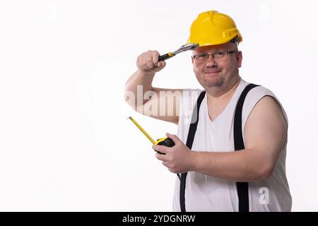 A Funny Construction Worker using various Tools and wearing a Yellow Hard Hat for safety Stock Photo